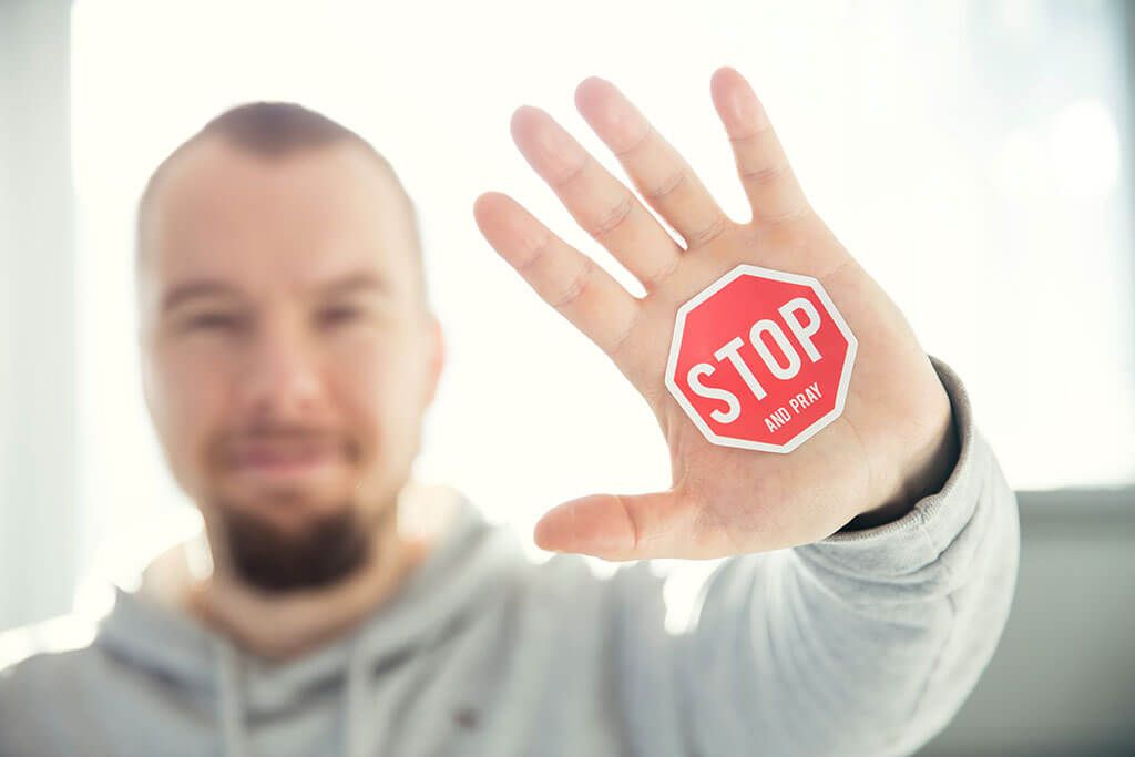 Hombre alzando la mano con una señal de stop
